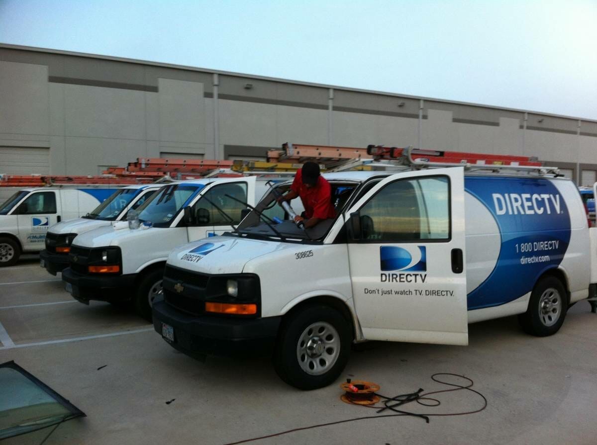 Depicted in this image are three of our technicians, meticulously working on replacing damaged front windshields of a DirecTV fleet. The fleet vans, parked in a large lot at the DirecTV location in Monte Vista, Texas, sustained windshield damage due to road debris on service trips. The necessary full replacements are underway, demonstrating our capabilities in managing commercial auto glass appointments for corporate fleets.